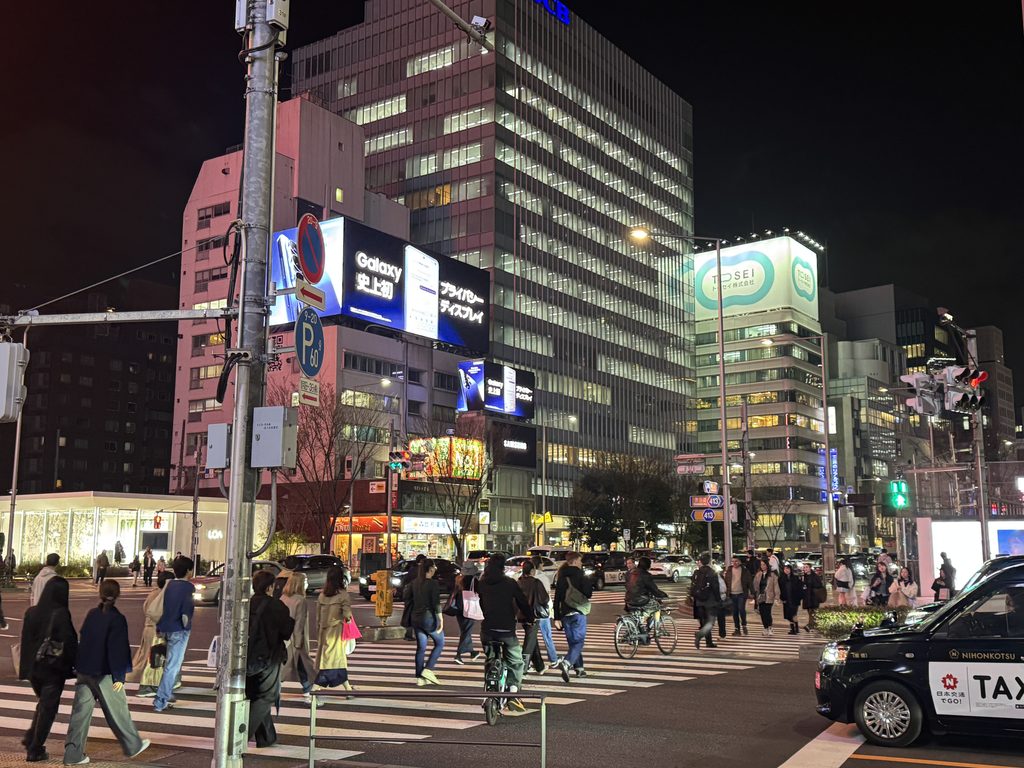 ビルのネオンと横断歩道を渡る人々